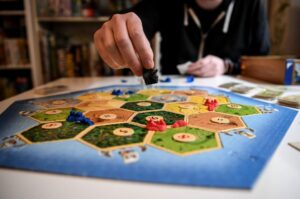 Catan board game set with modular tiles, player pieces, and dice, showcasing its iconic strategy and negotiation gameplay.