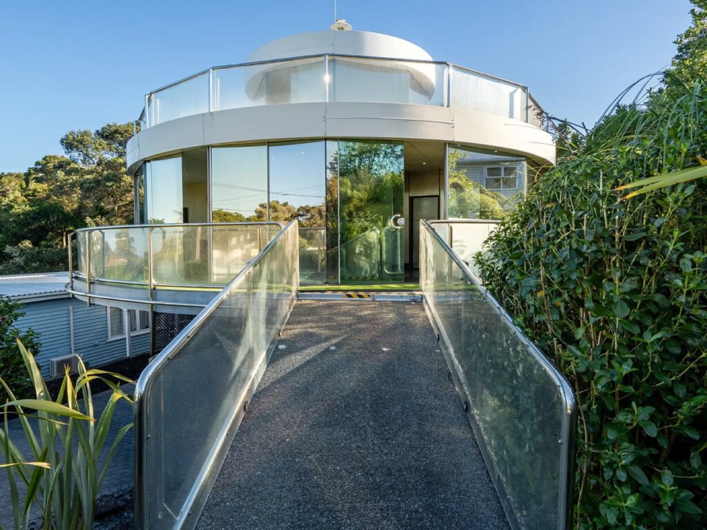 A sleek Circular Glass House with transparent walls, rotating on a central hub, offering panoramic 360-degree views.