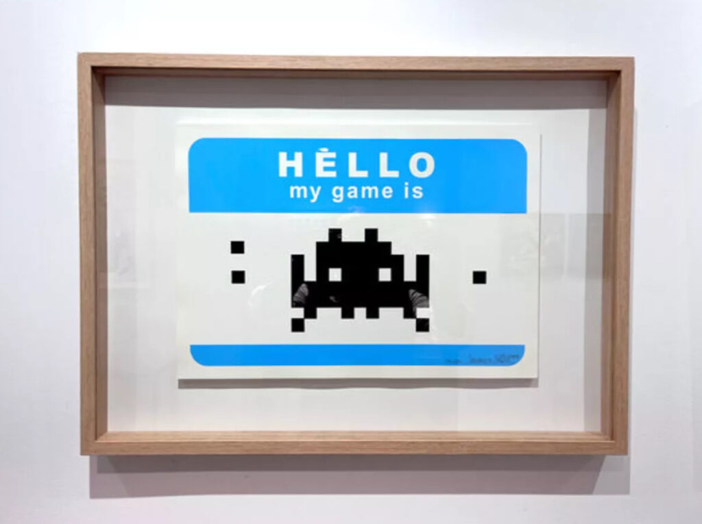 Invader’s 2009 screenprint Hello My Game Is featuring a pixelated Space Invader on a retro-inspired name badge design.