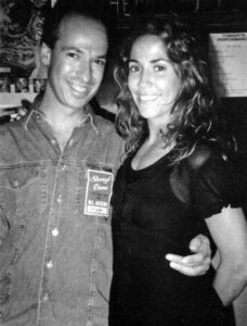 Sheryl Crow and Wyn Cooper, captured together, symbolizing their artistic collaboration on the song “All I Wanna Do,” which was inspired by Cooper’s poem “Fun.” The image highlights the fusion of music and poetry, showcasing the creative partnership that brought renewed attention to both artists.