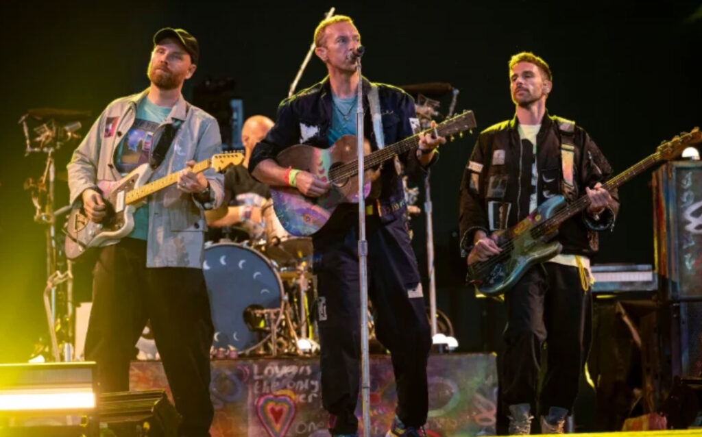 Coldplay rehearsing at the Cheese and Grain in Frome, Somerset, with instruments and a vibrant community-focused atmosphere.