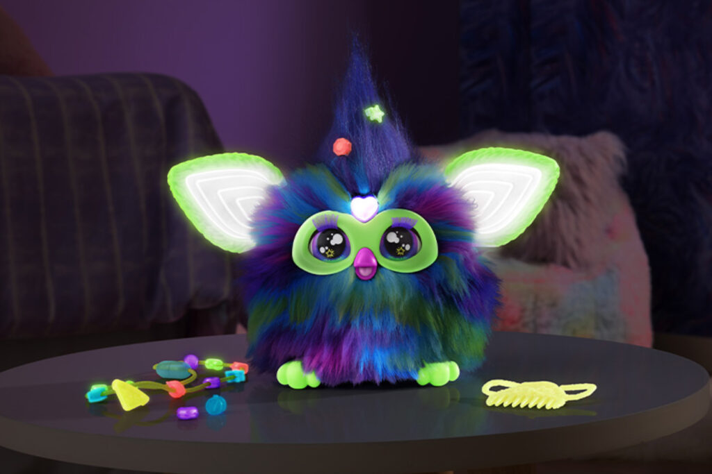 A glow-in-the-dark Furby Galaxy Edition toy with luminous ears, cosmic patterns, and interactive accessories.