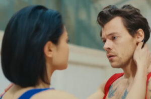 Harry Styles performing As It Was in a bold red jumpsuit, symbolizing vulnerability and artistic transformation