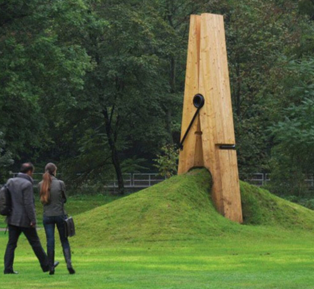 A giant clothespin sculpture by Mehmet Ali Uysal in Chaudfontaine, Belgium, appearing to pinch the earth in a public park