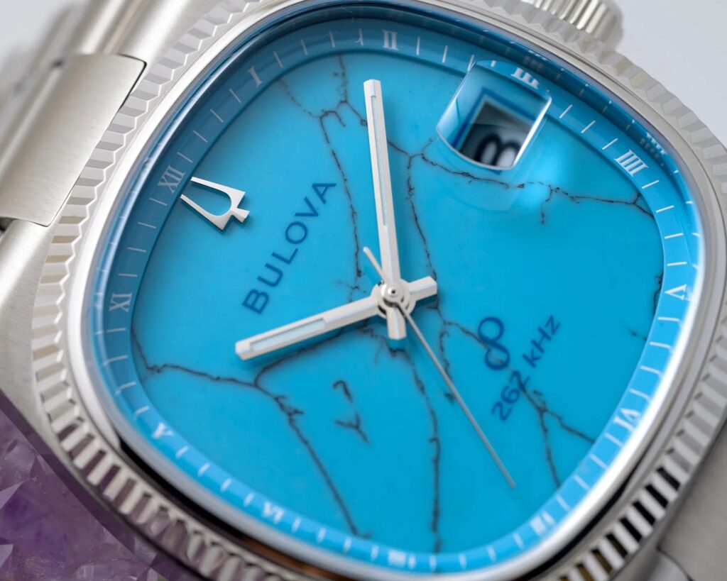 A Bulova watch with a turquoise dial showcasing natural veining, encased in a polished gold-tone frame with a leather strap