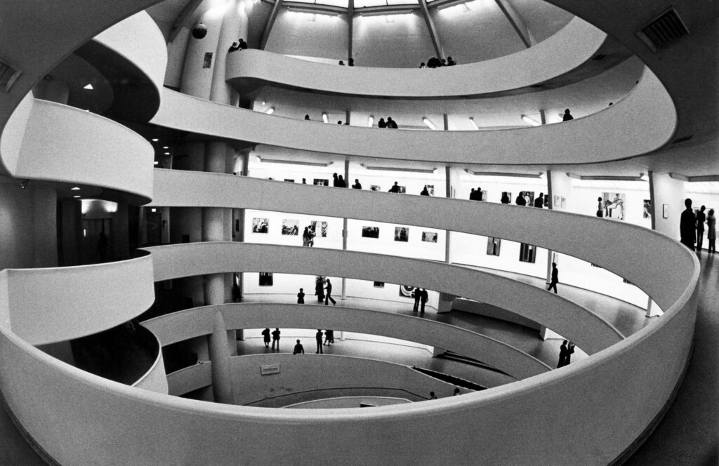 Interior view of the Guggenheim Museum’s iconic spiral rotunda, featuring vibrant art installations and visitors admiring works