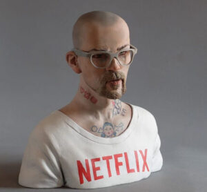 The sculpture Modern Junkie Chico by Javier Aguilera, featuring a slumped figure with a “Netflix” shirt, symbolizing digital addiction