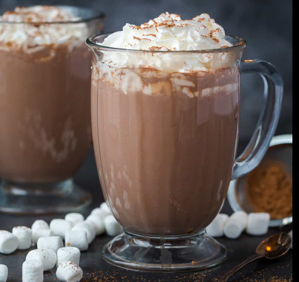 Two cups of hot chocolate side by side, one creamy with milk and the other pure with water, on a cozy wooden table