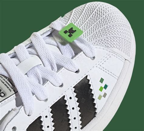 The Minecraft x Adidas Superstar Creeper sneaker featuring pixelated green accents and a Creeper face lace charm