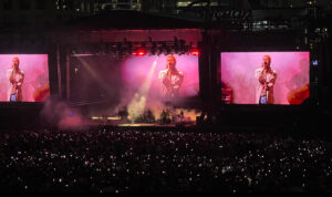 Post Malone performing onstage at the Wild Horses Festival 2025, engaging with a massive crowd under vibrant stage lighting