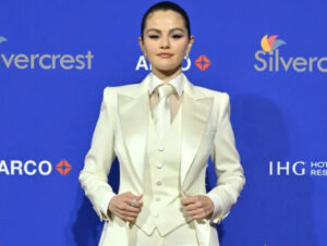 Selena Gomez poses in a tailored white tuxedo with satin lapels, paired with pointed heels and soft waves, redefining bridal style