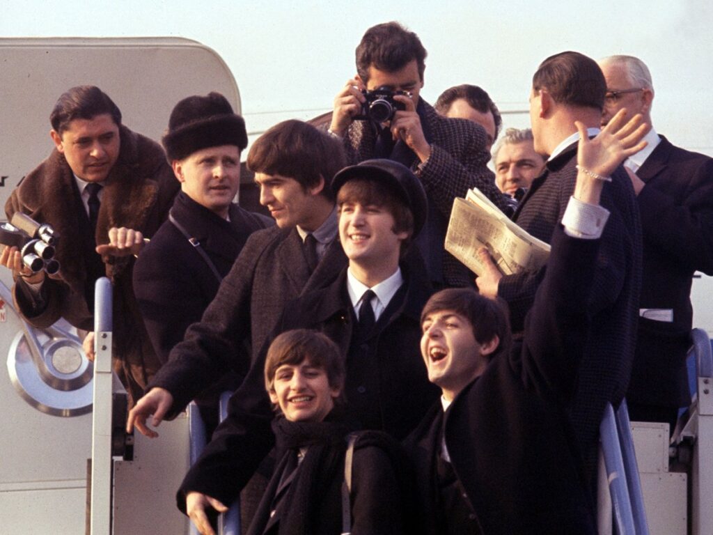 Archival footage from the Beatles ’64 documentary showing The Beatles arriving at Kennedy Airport surrounded by fans