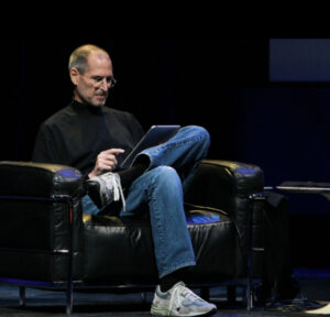 Steve Jobs wearing a black turtleneck, blue Levi’s jeans, and New Balance sneakers, representing his iconic uniform.