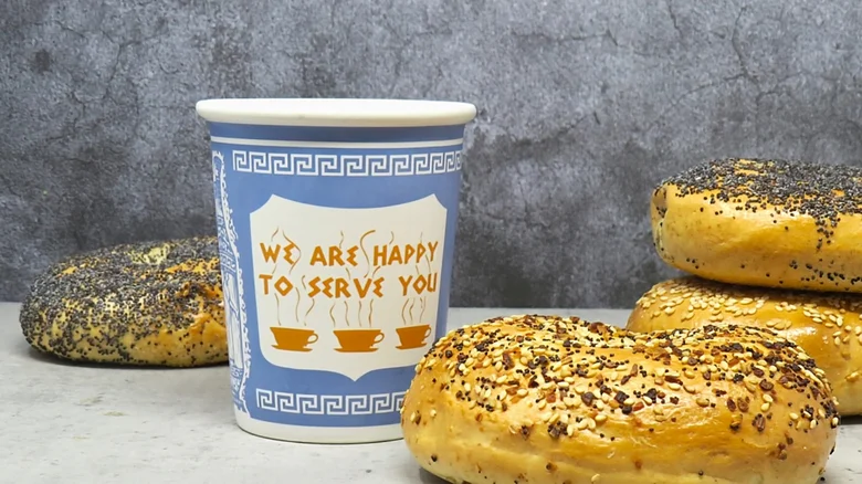 Anthora coffee cup, blue-and-white design with the phrase ‘We are happy to serve you,’ representing NYC coffee culture