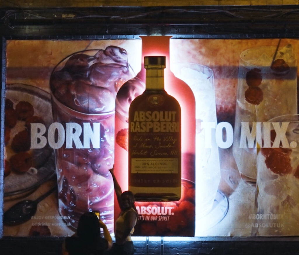 Absolut’s Born to Mix campaign installation featuring vibrant hyper-realistic cocktail art, 3D bottle-shaped panels, and LED lighting
