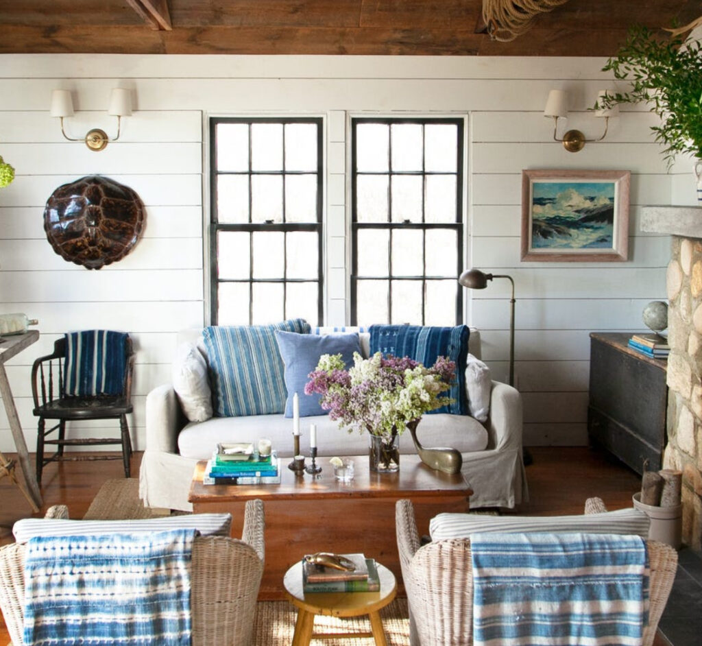A cozy interior featuring fisherman-inspired decor, including cable-knit throws, nautical elements, and earthy tones