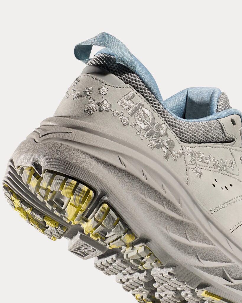 The Vibrant Bloom Bondi L, a stylish and cushioned shoe by HOKA, featuring floral embroidery and a marbled outsole