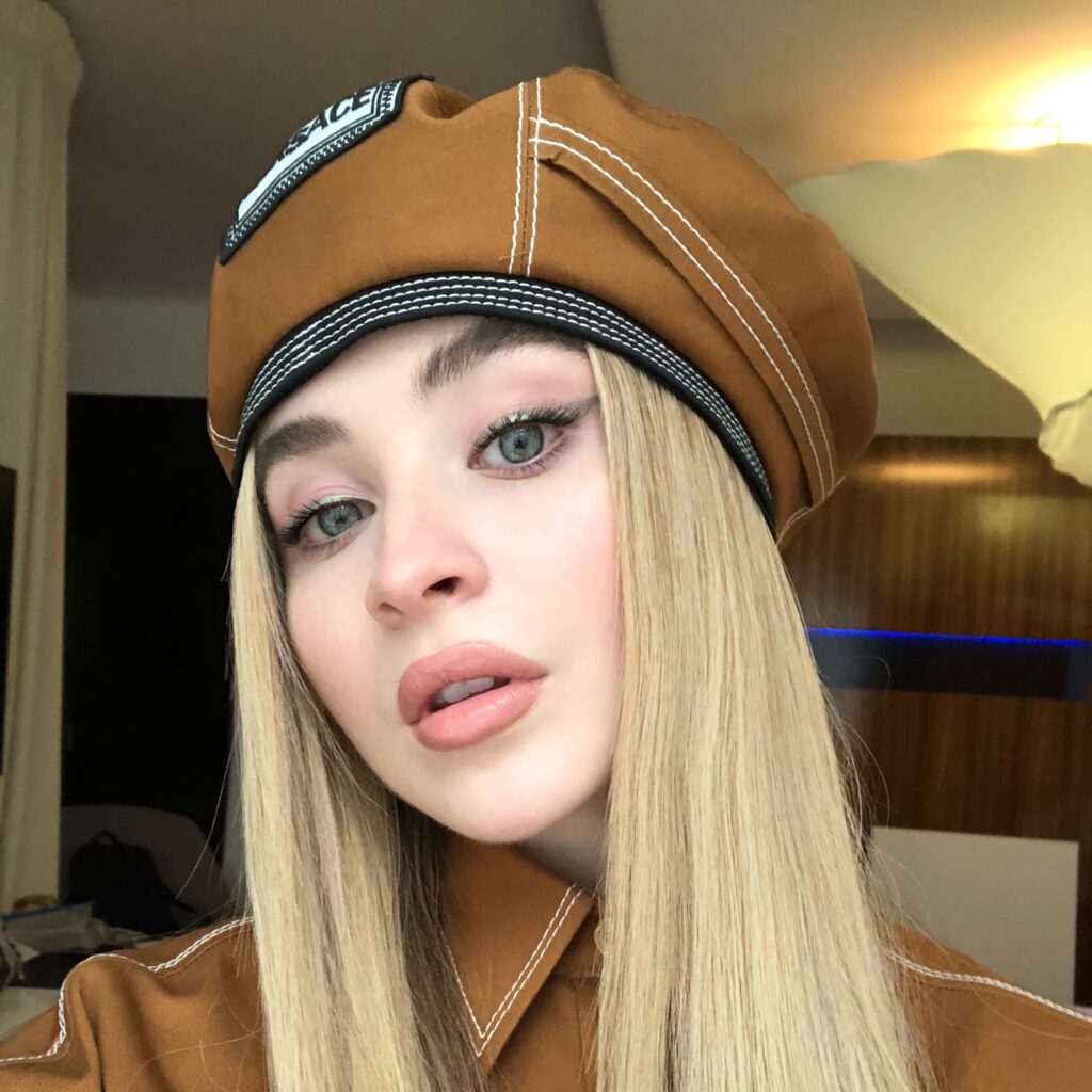Sabrina Carpenter in a photo shoot blending Prada’s minimalist tailoring with Versace’s bold, opulent patterns and textures