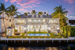 A luxurious Georgian-style mansion in Boca Raton with a waterfront pool, tropical landscaping, and private Intracoastal dock