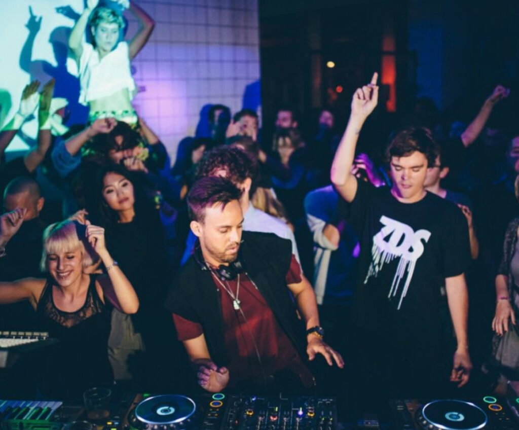 A DJ performing live at a Boiler Room event with a crowd in an intimate venue, highlighting the raw energy of the session