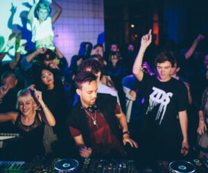 A DJ performing live at a Boiler Room event with a crowd in an intimate venue, highlighting the raw energy of the session
