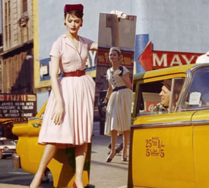 A black-and-white photograph by William Klein featuring Anne and Isabella with a mirror reflecting a taxi in Times Square, 1959