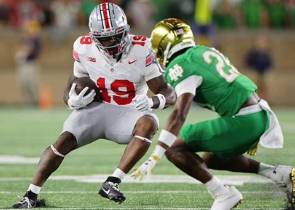 Notre Dame and Ohio State players in action during the national championship game, with the stadium packed with fans