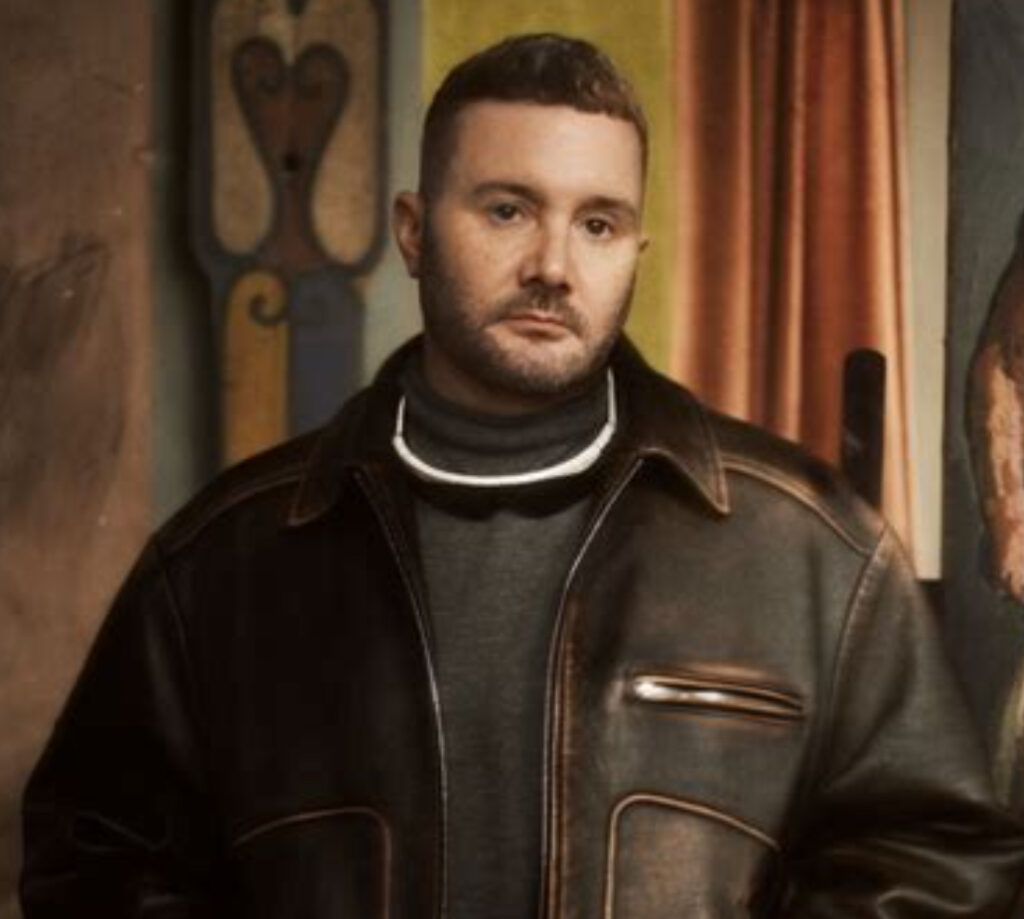 Kim Jones receiving the Légion d’Honneur in Paris, wearing a tailored suit, standing alongside fashion industry leaders