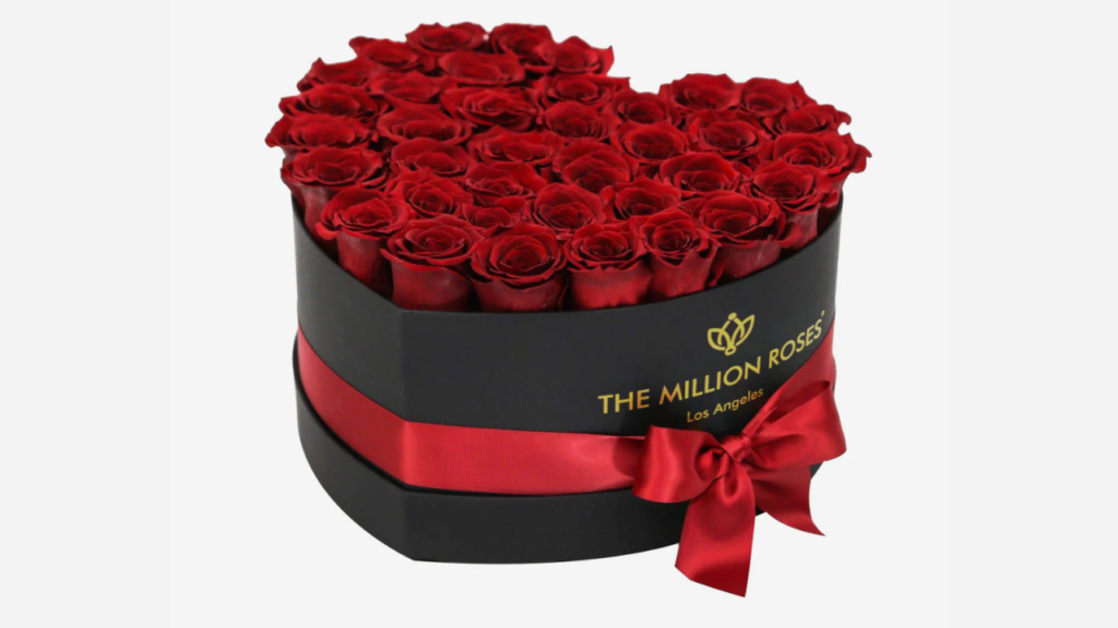 A luxurious black heart-shaped box filled with vibrant, preserved roses in various colors, for Valentine’s Day