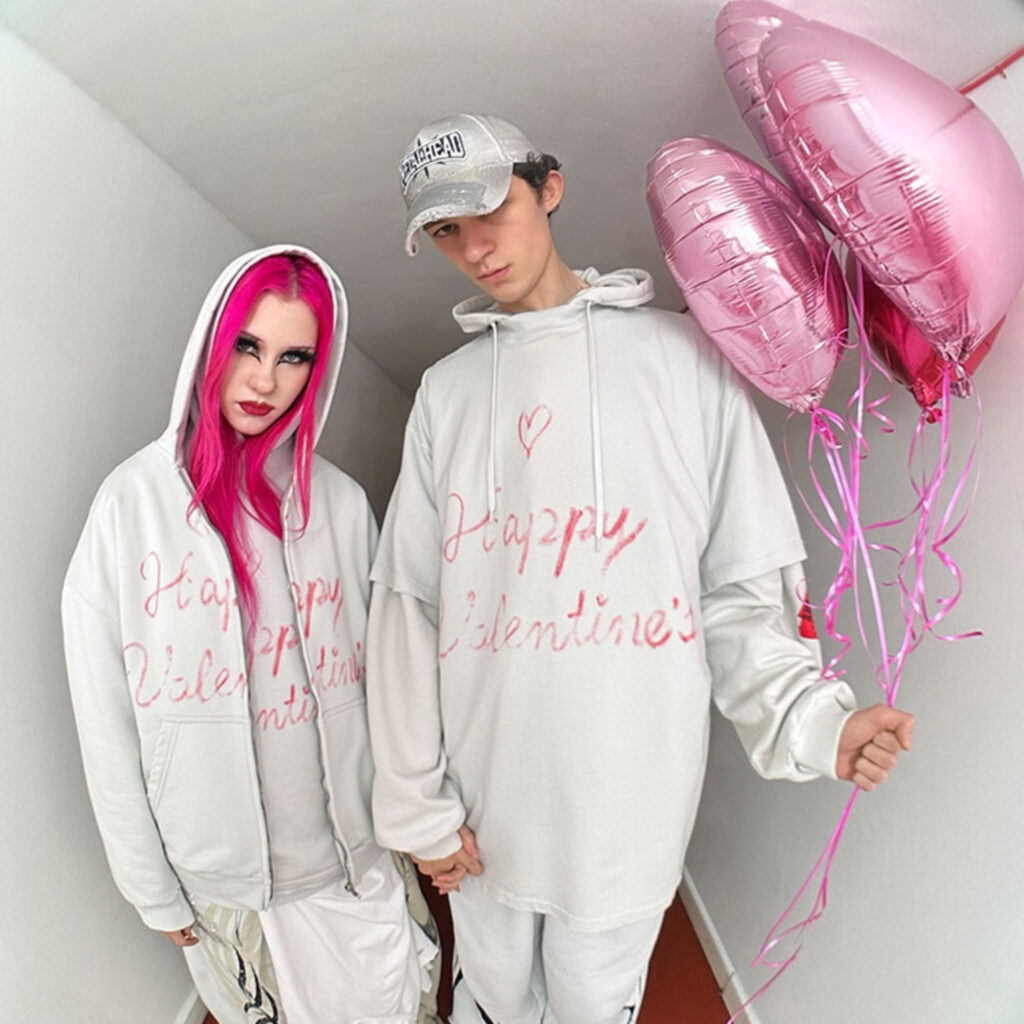 A model wearing a Balenciaga Valentine Series 2025 hoodie with handwritten love messages, framed through a door’s peephole