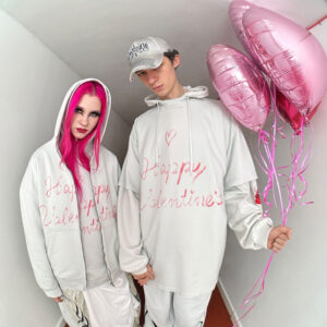 A model wearing a Balenciaga Valentine Series 2025 hoodie with handwritten love messages, framed through a door’s peephole