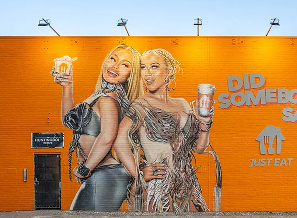 A vibrant mural depicting Christina Aguilera and Latto, part of Just Eat’s UK-wide outdoor advertising campaign