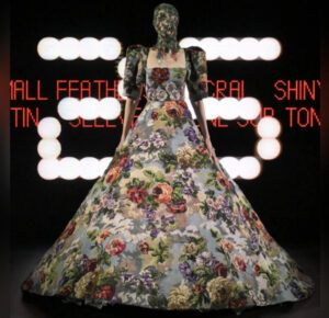 A model in an opulent Valentino haute couture gown strides through dramatic strobe lights, capturing the essence of Alessandro Michele’s visionary debut