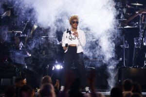 Janelle Monáe performing onstage at the 67th GRAMMY Awards, illuminated by vibrant stage lighting and futuristic visuals