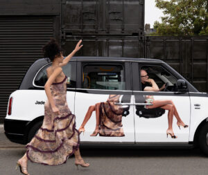 A Jaded London-branded taxi featuring bold, streetwear-inspired graphics, driving through the vibrant city streets