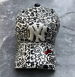 A hyper-realistic ceramic sculpture of a NY Yankees baseball cap by Yael Yanay, capturing the essence of street art and sports culture