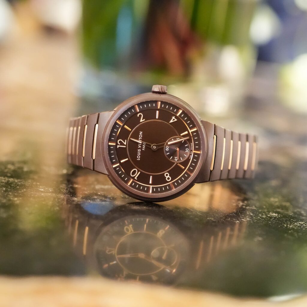 A close-up of the Louis Vuitton Tambour Ceramic, showcasing its brown high-tech ceramic case with 18k rose gold accents