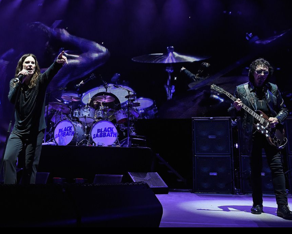 Ozzy Osbourne performing on stage at his final concert with Black Sabbath, surrounded by an electrifying heavy metal crowd