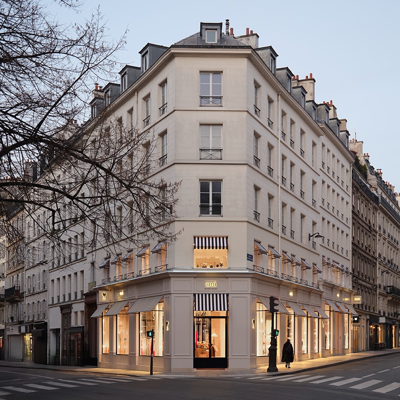 AMI Paris flagship store featuring elegant interiors with Euville stone, warm wood accents, and a sustainable fashion program
