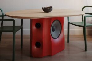 Joel Seigle's Subwoofer Dining Table, showcasing a solid ash construction, neutral-colored tabletop, and integrated JBL2226h driver in a bold iridescent red finish