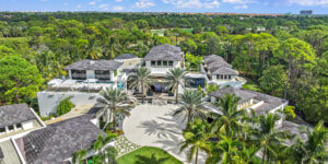 Aerial view of a luxurious mansion with a sprawling garden and pool, exemplifying high-end real estate