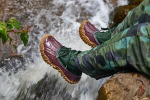 A pair of Crocs Cypress Boots trekking through a rugged, outdoor landscape, showcasing their adventurous spirit
