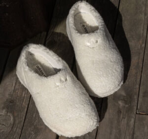 A pair of fleece-lined Adidas Stan Smith Mules in a creamy white color, showcasing their cozy texture and stylish slip-on design