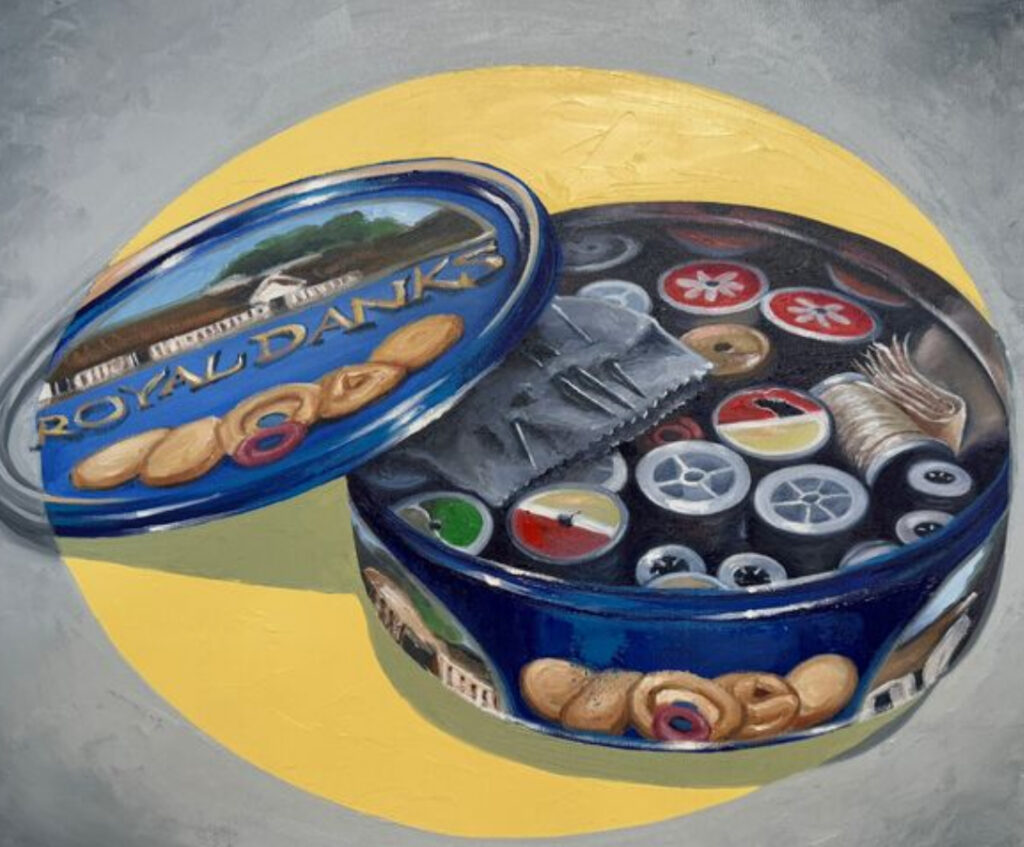 A vintage blue cookie tin filled with Danish butter cookies, next to a sewing kit, symbolizing nostalgia and tradition