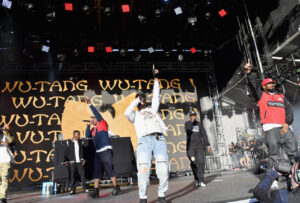 Wu-Tang Clan performing on stage with the iconic “W” logo glowing behind them