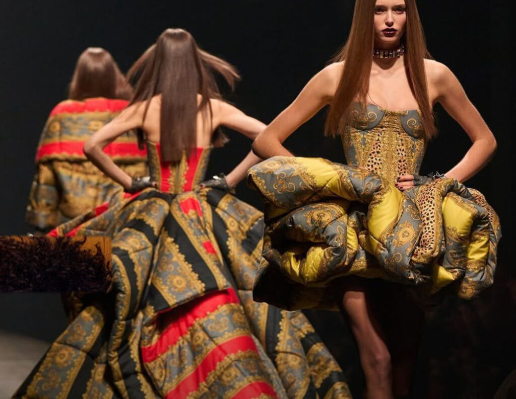 Versace runway model in bold print outfit, symbolizing the brand’s identity amid Prada’s high-profile acquisition plans