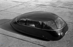 The 1939 Schlörwagen “Pillbug,” a teardrop-shaped silver prototype car with covered wheels and flush windows, on display
