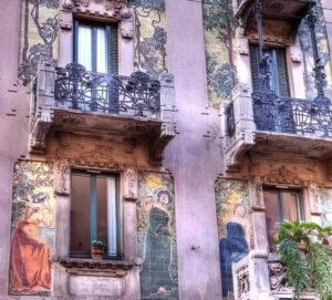 Exterior view of Casa Galimberti in Milan, showcasing vibrant majolica tiles, floral ironwork, and Liberty-style details