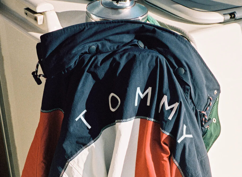 Tommy Hilfiger model wearing color-block sailing jacket and nautical pants from 2025 capsule, standing on yacht deck