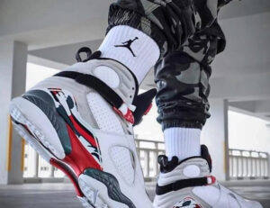 Air Jordan 8 “Bugs Bunny” 2025 sneakers shown on-foot with camo pants and white Jordan socks in a modern urban setting